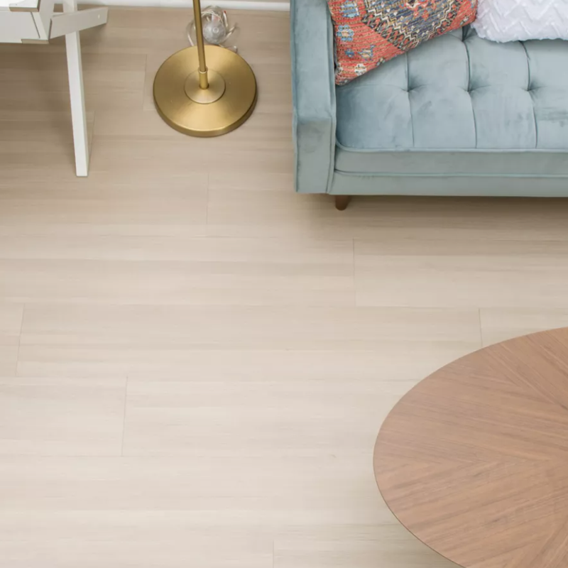 Light vinyl flooring in a small living space with a white desk chair and blue sofa